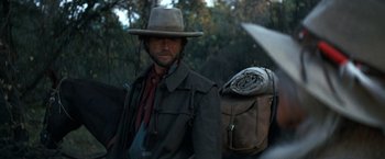 Movie still from “The Outlaw Josey Wales” (1976), directed by Clint Eastwood – A man in a hat and a jacket with a backpack; Close Up shot, Over the shoulder angle