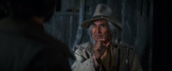 Movie still from “The Outlaw Josey Wales” (1976), directed by Clint Eastwood – An old man with a hat smoking a cigarette in front of a mirror; Close Up shot, Over the shoulder angle