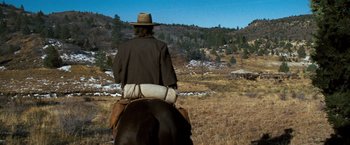 Movie still from “The Outlaw Josey Wales” (1976), directed by Clint Eastwood – A man riding on the back of a brown horse; Wide shot, Over the shoulder angle