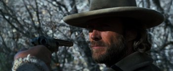 Movie still from “The Outlaw Josey Wales” (1976), directed by Clint Eastwood – A man with a hat and a gun in his hand; Close Up shot, Over the shoulder angle