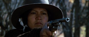 Movie still from “The Outlaw Josey Wales” (1976), directed by Clint Eastwood – A woman holding a gun while wearing a hat; Close Up shot, Low angle