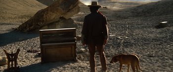Movie still from “The Outlaw Josey Wales” (1976), directed by Clint Eastwood – A man and a dog standing next to a trunk; Wide shot, Low angle