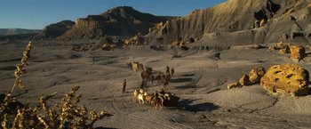Movie still from “The Outlaw Josey Wales” (1976), directed by Clint Eastwood – A group of people on a dirt field with horses; Extreme Wide shot, High angle