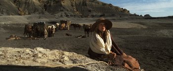 Movie still from “The Outlaw Josey Wales” (1976), directed by Clint Eastwood – A woman sitting on the ground in front of a herd of cattle; Wide shot, High angle