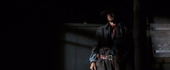 Movie still from “The Outlaw Josey Wales” (1976), directed by Clint Eastwood – A man wearing a cowboy hat and holding a gun; Medium shot, Low angle
