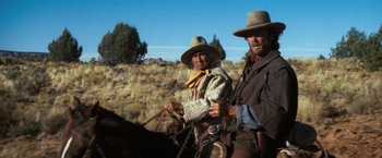 Movie still from “The Outlaw Josey Wales” (1976), directed by Clint Eastwood – A man and a woman on a horse in a field; Medium shot, Low angle