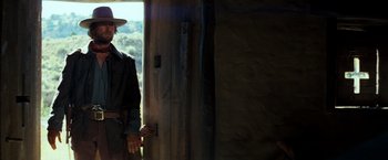 Movie still from “The Outlaw Josey Wales” (1976), directed by Clint Eastwood – A man standing in front of an open door; Medium shot, Over the shoulder angle