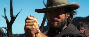 Movie still from “The Outlaw Josey Wales” (1976), directed by Clint Eastwood – A man in a cowboy hat is holding his hands together; Close Up shot, Low angle