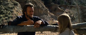 Movie still from “The Outlaw Josey Wales” (1976), directed by Clint Eastwood – A man and a woman sitting on a wooden fence; Close Up shot, Over the shoulder angle