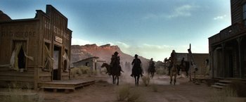 Movie still from “The Outlaw Josey Wales” (1976), directed by Clint Eastwood – A group of men riding horses down a dirt road; Extreme Wide shot, Low angle