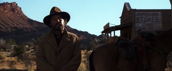 Movie still from “The Outlaw Josey Wales” (1976), directed by Clint Eastwood – A man wearing a hat standing next to a horse; Medium shot, Low angle