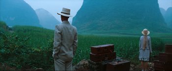 Movie still from “The Painted Veil” (2006), directed by John Curran – A man standing in front of some suitcases in a field; Wide shot, Over the shoulder angle