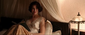 Movie still from “The Painted Veil” (2006), directed by John Curran – A woman sitting on a bed holding a book; Medium shot, High angle