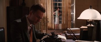 Movie still from “The Painted Veil” (2006), directed by John Curran – A man sitting at a table with a typewriter; Medium shot, Over the shoulder angle
