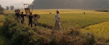 Movie still from “The Painted Veil” (2006), directed by John Curran – A man in a suit and hat is walking through a field; Wide shot, High angle