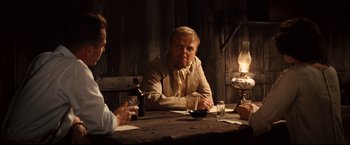 Movie still from “The Painted Veil” (2006), directed by John Curran – A man sitting at a table in front of two other men; Medium shot, Over the shoulder angle