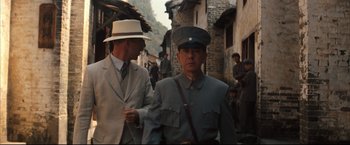 Movie still from “The Painted Veil” (2006), directed by John Curran – A man in a suit and hat walking down a street; Medium shot, Over the shoulder angle