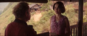 Movie still from “The Painted Veil” (2006), directed by John Curran – A woman in a pink dress talking to a man in front of a house; Medium shot, Over the shoulder angle