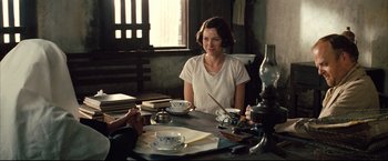 Movie still from “The Painted Veil” (2006), directed by John Curran – A woman sitting at a table with a cup of tea; Medium shot, Over the shoulder angle