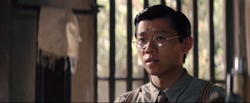 Movie still from “The Painted Veil” (2006), directed by John Curran – A man wearing glasses and a tie looking to his left; Close Up shot, Over the shoulder angle