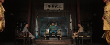 Movie still from “The Painted Veil” (2006), directed by John Curran – A man sitting on top of a chair in front of a fire place; Wide shot, Low angle