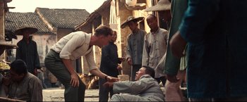Movie still from “The Painted Veil” (2006), directed by John Curran – A group of men standing around a man in the street; Medium shot, Over the shoulder angle