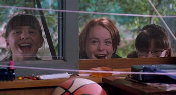 Movie still from “The Parent Trap” (1998), directed by Nancy Meyers – A young girl smiles through a screen door; Medium shot, Low angle
