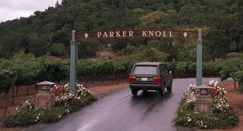 Movie still from “The Parent Trap” (1998), directed by Nancy Meyers – A car driving down a road under a sign; Extreme Wide shot, High angle