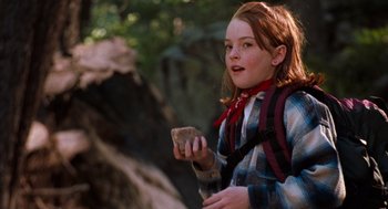 Movie still from “The Parent Trap” (1998), directed by Nancy Meyers – A young girl holding a piece of wood while standing in the woods; Close Up shot, Over the shoulder angle