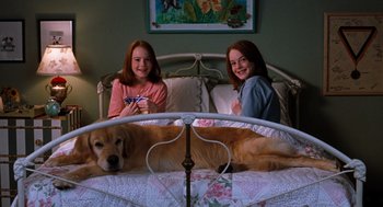 Movie still from “The Parent Trap” (1998), directed by Nancy Meyers – Two young girls sitting in a bed with a dog; Wide shot, High angle