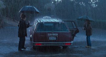 Movie still from “The Parent Trap” (1998), directed by Nancy Meyers – A woman holding an umbrella standing next to a taxi cab; Wide shot, Low angle