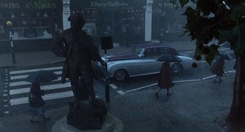 Movie still from “The Parent Trap” (1998), directed by Nancy Meyers – A statue of a man holding an umbrella on a rainy day; Wide shot, High angle