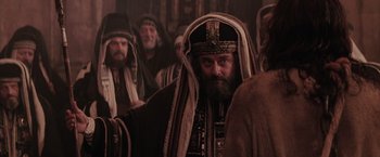 Movie still from “The Passion of the Christ” (2004), directed by Mel Gibson – A man in a beard and a turban is in front of a group of people; Medium shot, Over the shoulder angle