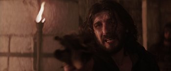 Movie still from “The Passion of the Christ” (2004), directed by Mel Gibson – A man with long hair and a beard holding a gun; Close Up shot, Over the shoulder angle