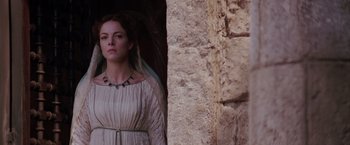 Movie still from “The Passion of the Christ” (2004), directed by Mel Gibson – A woman standing in front of a stone wall; Medium shot, Low angle
