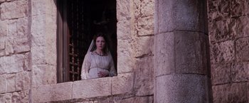 Movie still from “The Passion of the Christ” (2004), directed by Mel Gibson – A woman wearing a veil standing next to a stone wall; Medium shot, Low angle