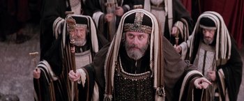 Movie still from “The Passion of the Christ” (2004), directed by Mel Gibson – A man with a long beard and a long crown holding a staff; Close Up shot, High angle