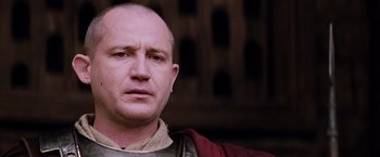 Movie still from “The Passion of the Christ” (2004), directed by Mel Gibson – A bald man in a red shirt is looking straight ahead; Close Up shot, Low angle