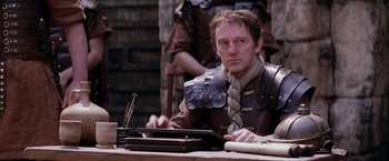 Movie still from “The Passion of the Christ” (2004), directed by Mel Gibson – A man sitting at a table writing on a piece of paper; Medium shot, Over the shoulder angle