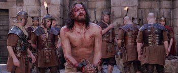 Movie still from “The Passion of the Christ” (2004), directed by Mel Gibson – A man with blood all over his face and body; Medium shot, Low angle