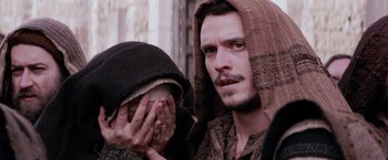 Movie still from “The Passion of the Christ” (2004), directed by Mel Gibson – A man in a hooded jacket holding his face; Close Up shot, Over the shoulder angle