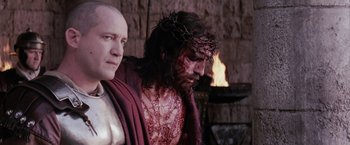 Movie still from “The Passion of the Christ” (2004), directed by Mel Gibson – A man with a crown of thorns and a man with a sword; Close Up shot, Over the shoulder angle