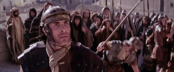 Movie still from “The Passion of the Christ” (2004), directed by Mel Gibson – A man in a roman soldier's outfit with other people in the background; Close Up shot, Low angle