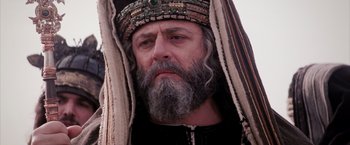 Movie still from “The Passion of the Christ” (2004), directed by Mel Gibson – An old man with long grey hair and a beard wearing a headdress; Close Up shot, Low angle