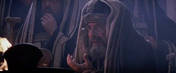 Movie still from “The Passion of the Christ” (2004), directed by Mel Gibson – An old man with a long beard wearing a headdress; Medium shot, Low angle