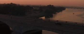 Movie still from “The Pelican Brief” (1993), directed by Alan J. Pakula – A view of a river and a bridge at dusk; Extreme Wide shot, High angle