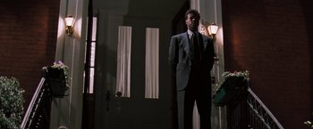 Movie still from “The Pelican Brief” (1993), directed by Alan J. Pakula – A man in a suit standing in front of a door; Medium shot, Low angle