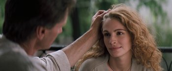 Movie still from “The Pelican Brief” (1993), directed by Alan J. Pakula – A man touching a woman's hair while she looks at the camera; Close Up shot, Over the shoulder angle