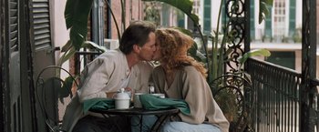 Movie still from “The Pelican Brief” (1993), directed by Alan J. Pakula – A man and a woman kissing at an outdoor table; Medium shot, Low angle