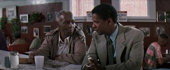 Movie still from “The Pelican Brief” (1993), directed by Alan J. Pakula – Two men sitting at a table talking to each other; Medium shot, Over the shoulder angle